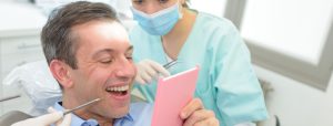 man looking at his new smile at the dentist